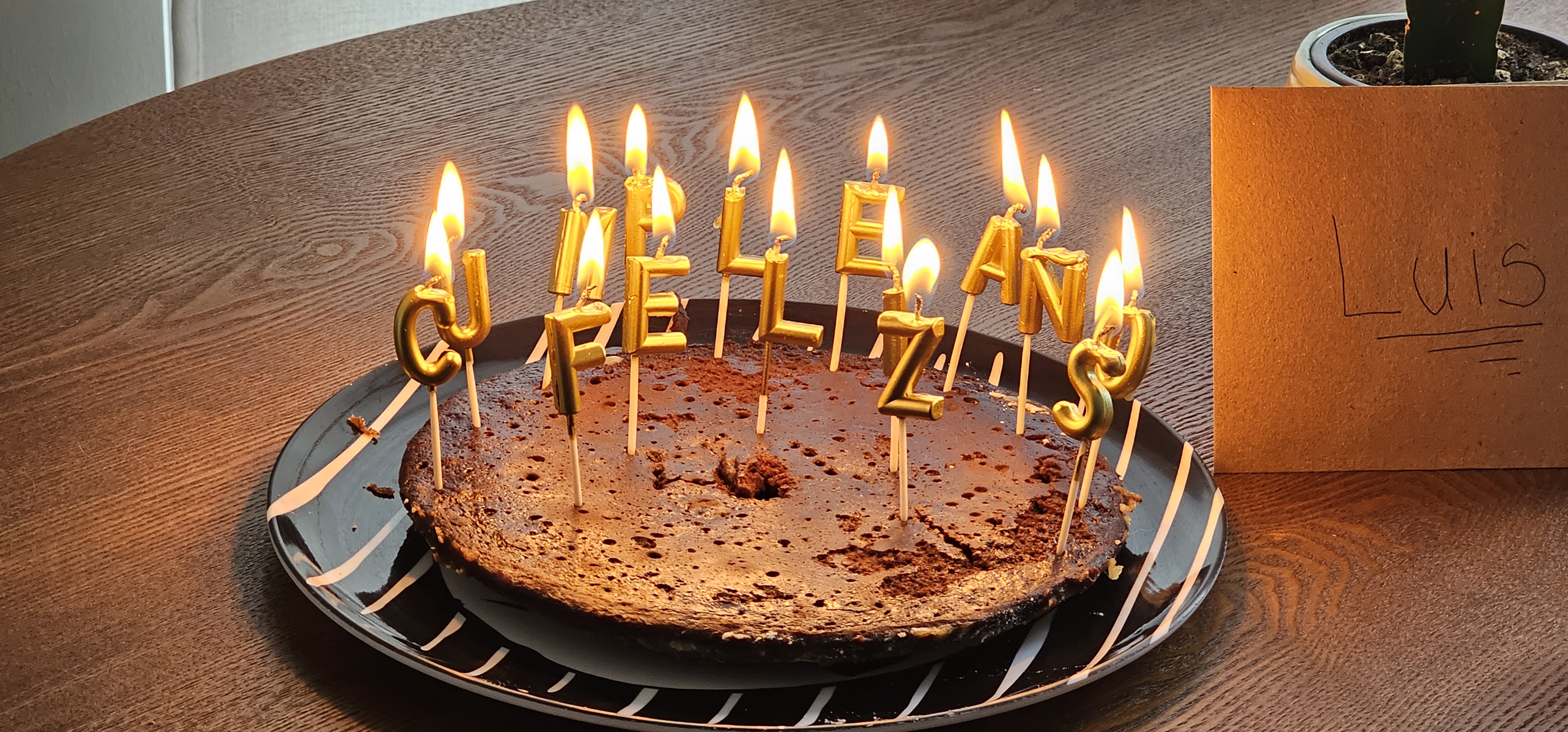 Picture of a birthday brownie with the candles spelling happy birthday in spanish.