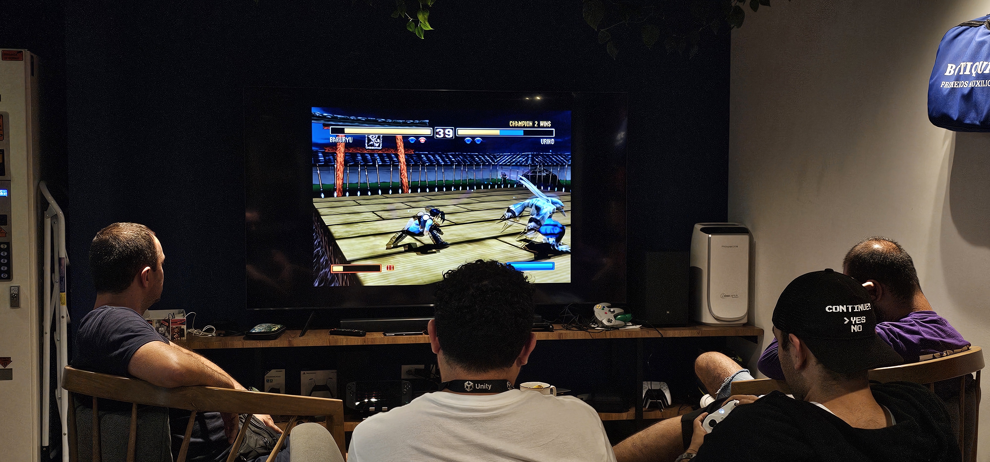 Picture of a group of dudes playing fighting games in front of a TV.